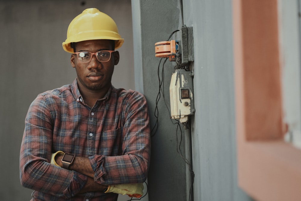 Portrait of a black man architect at a building site looking at camera. Confident civil engineering wearing a hardhat and eye goggles. Successful mature civil engineer at a construction site with open